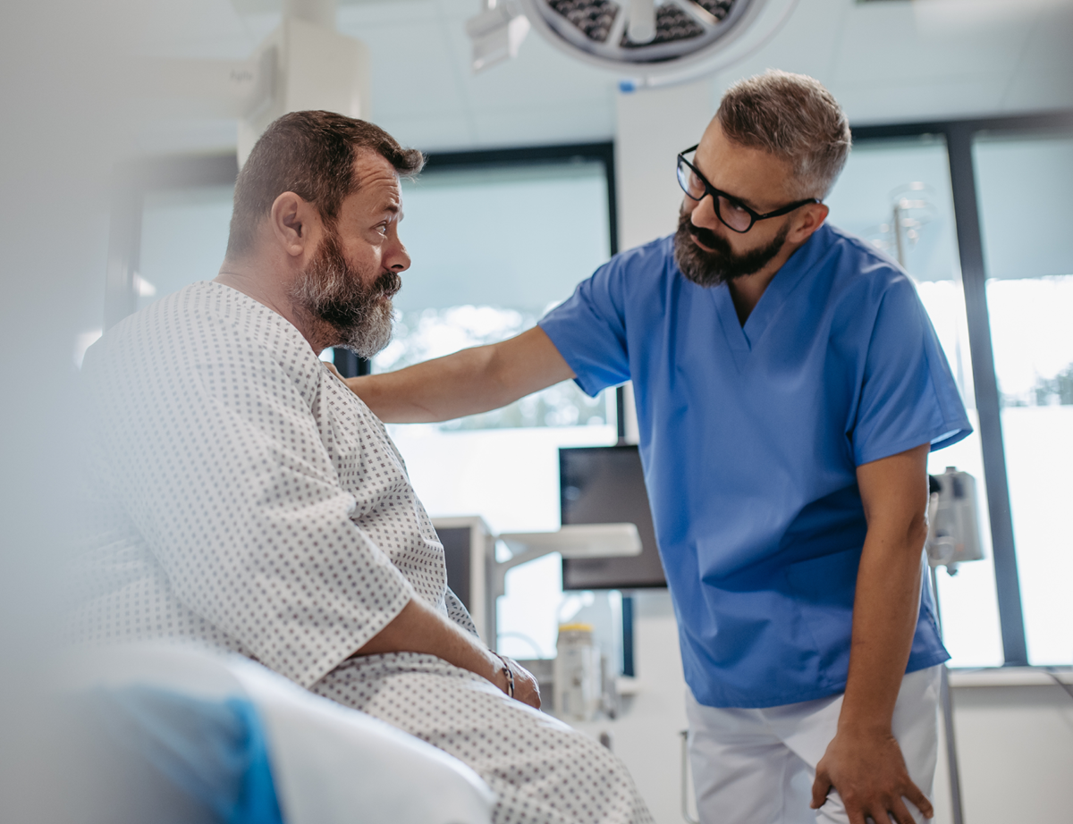 Supportive doctor soothing a worried overweight patient, discussing test result in emergency room. Illnesses and diseases in middle-aged men's health. Compassionate physician supporting stressed